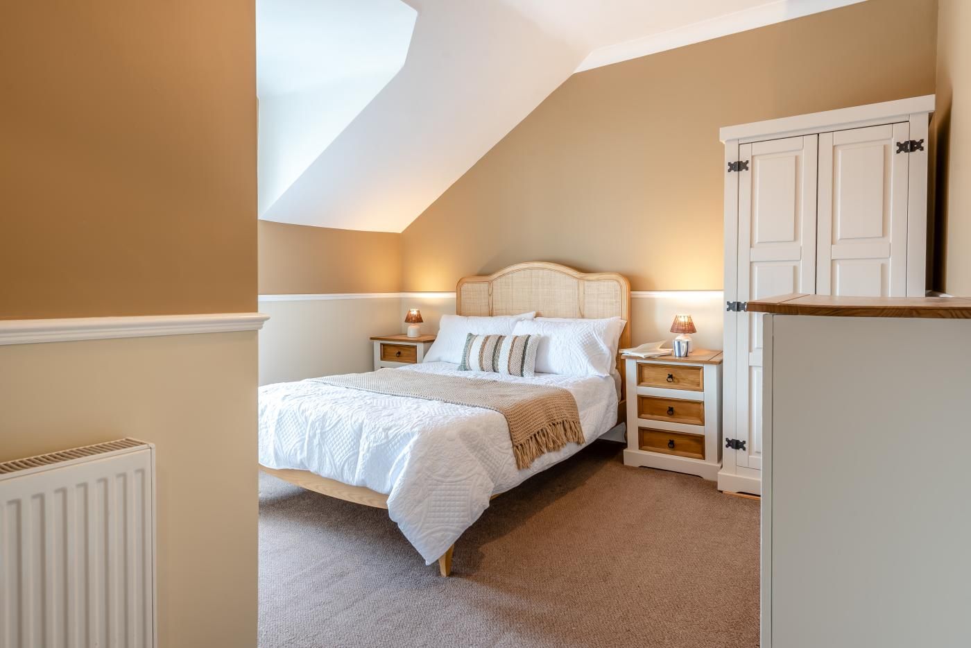 A bedroom with a bed, bedside tables, and a wardrobe.
