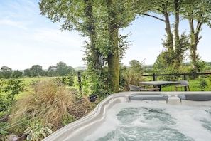 A hot tub with a view of a grassy field and trees.