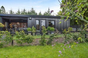 A modern building with a covered outdoor area, a visible entrance, and a garden with various plants and flowers. - 1 Bed in St. Anns (oc-s44941) (Saint Ann's)