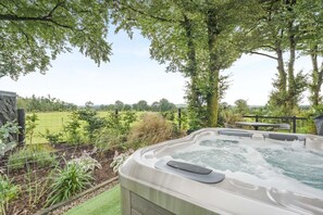 A hot tub with a view of a grassy field and trees.