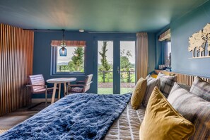 A bedroom with a bed, a chair, a table, and a view of the outdoors. - 1 Bed in St. Anns (oc-s44941) (Saint Ann's)