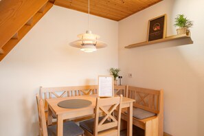 A wooden dining area with a table and benches, a hanging light fixture, a framed certificate on a shelf, and a potted plant. - Schwarzwaldmarie Apartment Schönwald: Balcony, Stunning View, Wi-Fi (Schönwald im Schwarzwald)