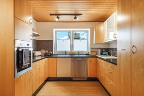 A modern kitchen with wooden cabinets, a black countertop, and a window with a view of the outdoors. - Schwarzwaldmarie Apartment Schönwald: Balcony, Stunning View, Wi-Fi (Schönwald im Schwarzwald)