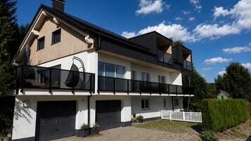 A two-story house with a garage, a balcony, and a well-maintained lawn.