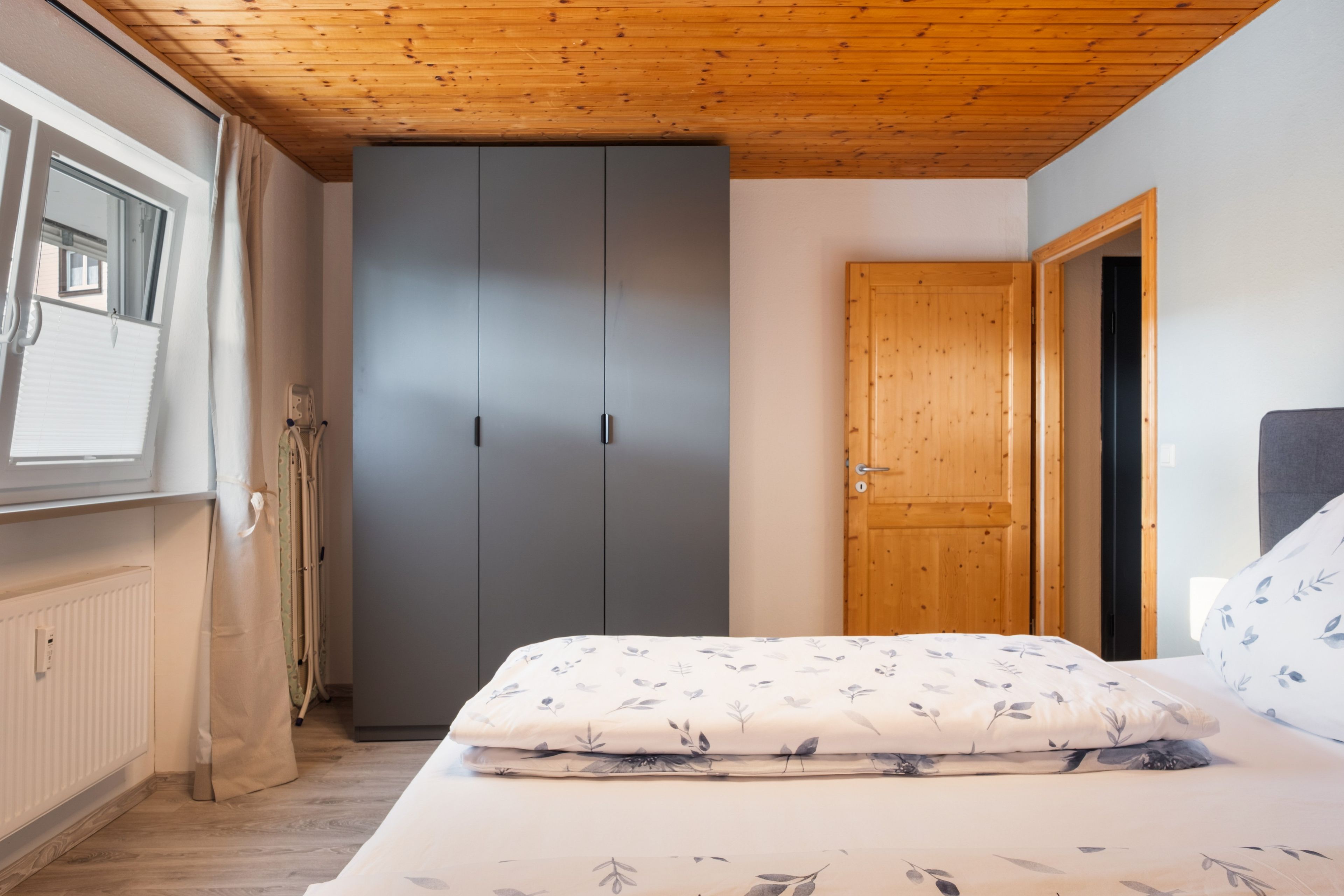 A bedroom with a bed, a wardrobe, and a door.