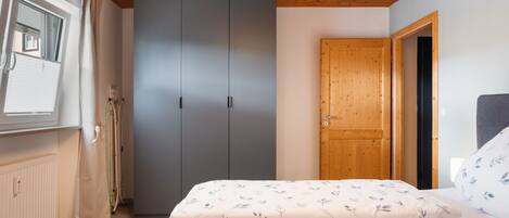 A bedroom with a bed, a wardrobe, and a door.