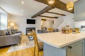 A modern living room with a fireplace, a dining area, and a kitchen with a large island.