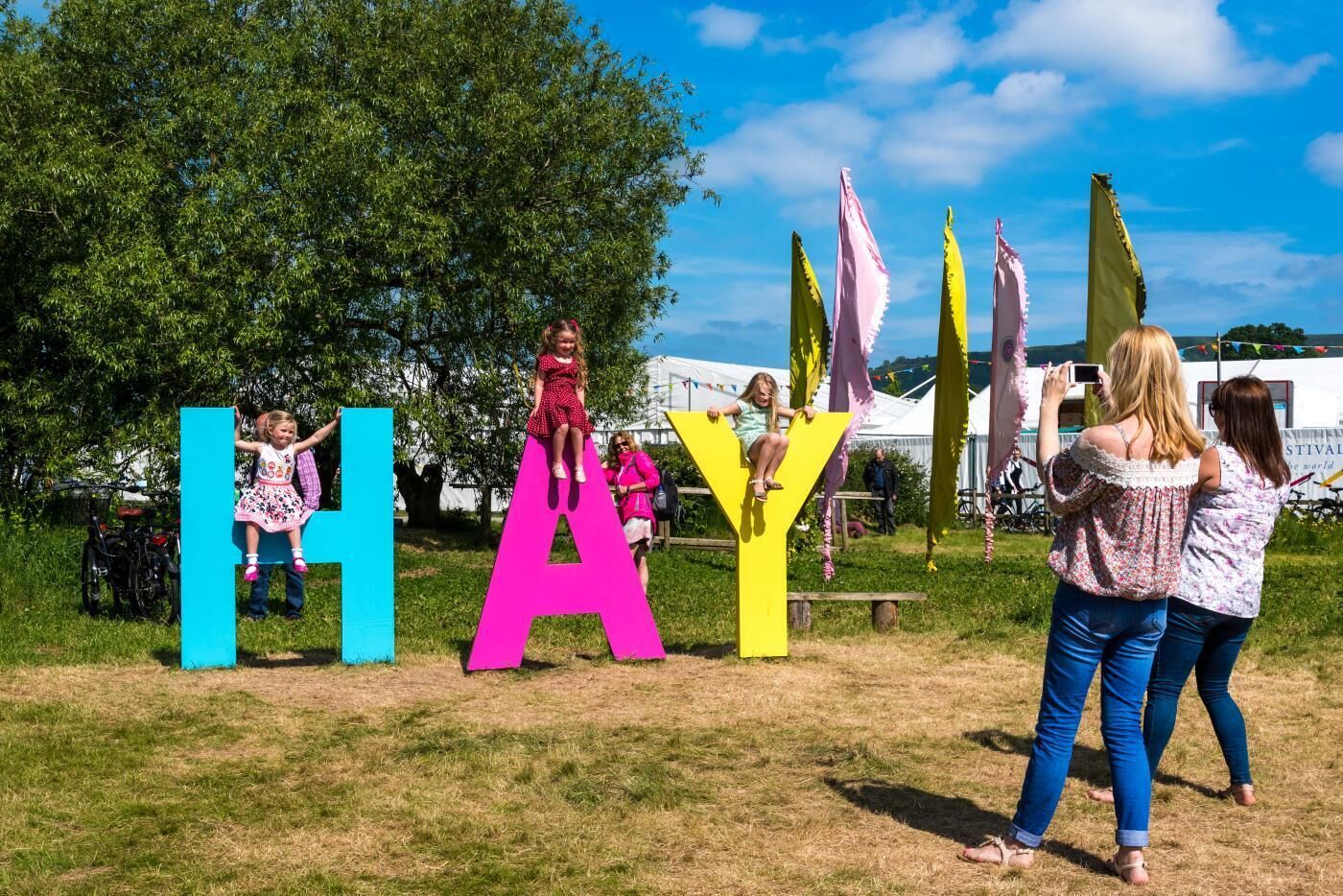 A grassy outdoor area with large colorful letters spelling 'HAY' and a bicycle parked nearby.