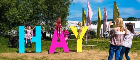 A grassy outdoor area with large colorful letters spelling 'HAY' and a bicycle parked nearby.