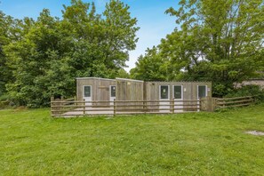 Eine Holzhütte mit zwei Türen, einem Holzzaun und einer Rasenfläche.