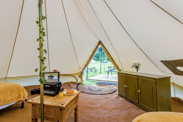 Ein Zeltinnenraum mit Tisch, Schrank und Blick ins Freie.