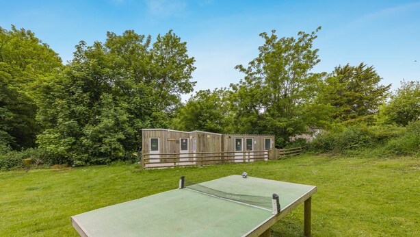 An outdoor ping pong table in a grassy area with a wooden structure in the background. - 1 Bed in St. Florence (oc-b33550) (Saint Florence)