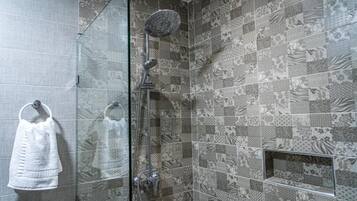 Ducha con puerta de vidrio y pared de azulejos con diseño.