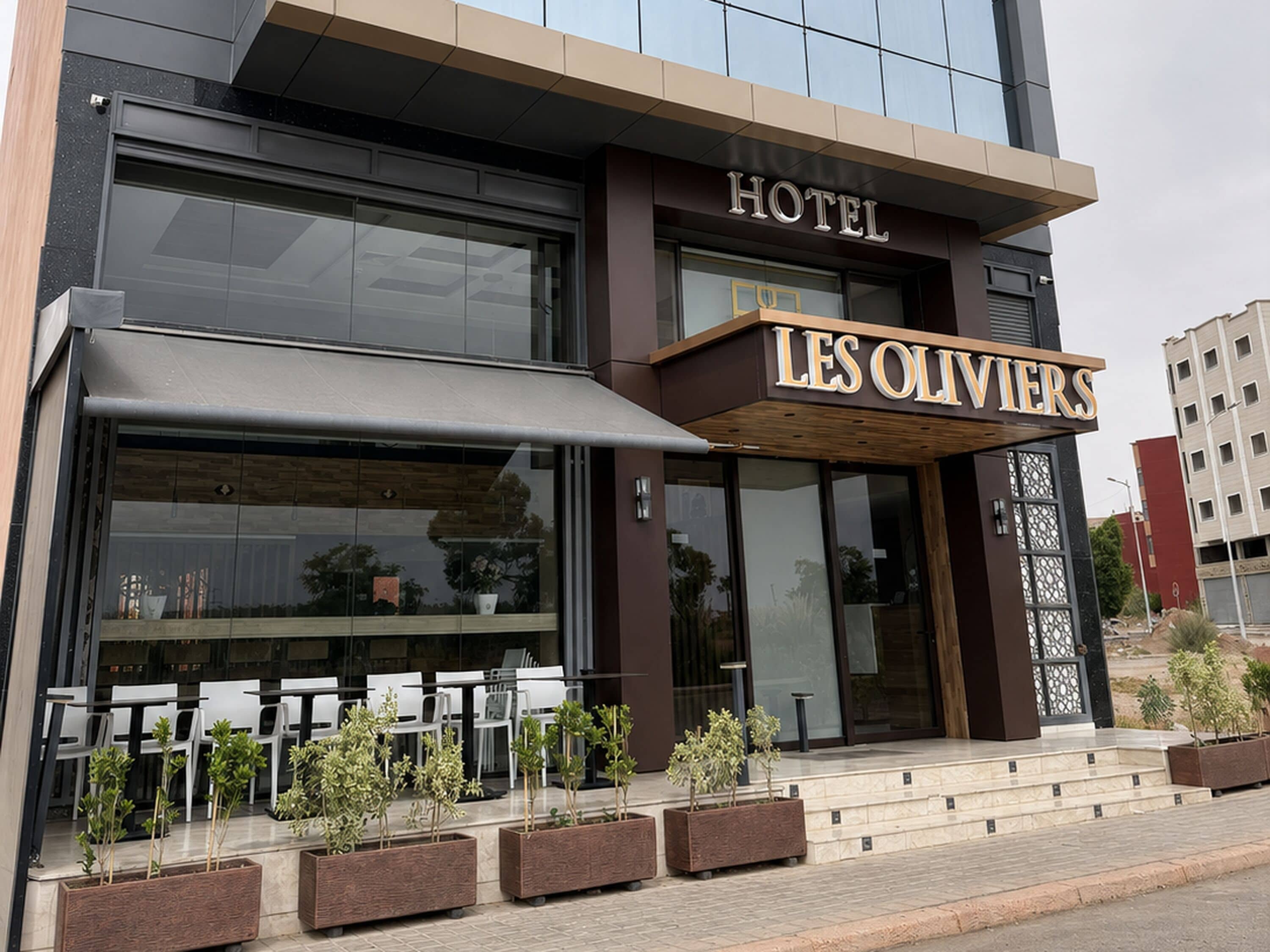 A hotel exterior with outdoor seating and potted plants.