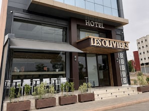 Exterior de un hotel con asientos al aire libre y plantas en macetas.