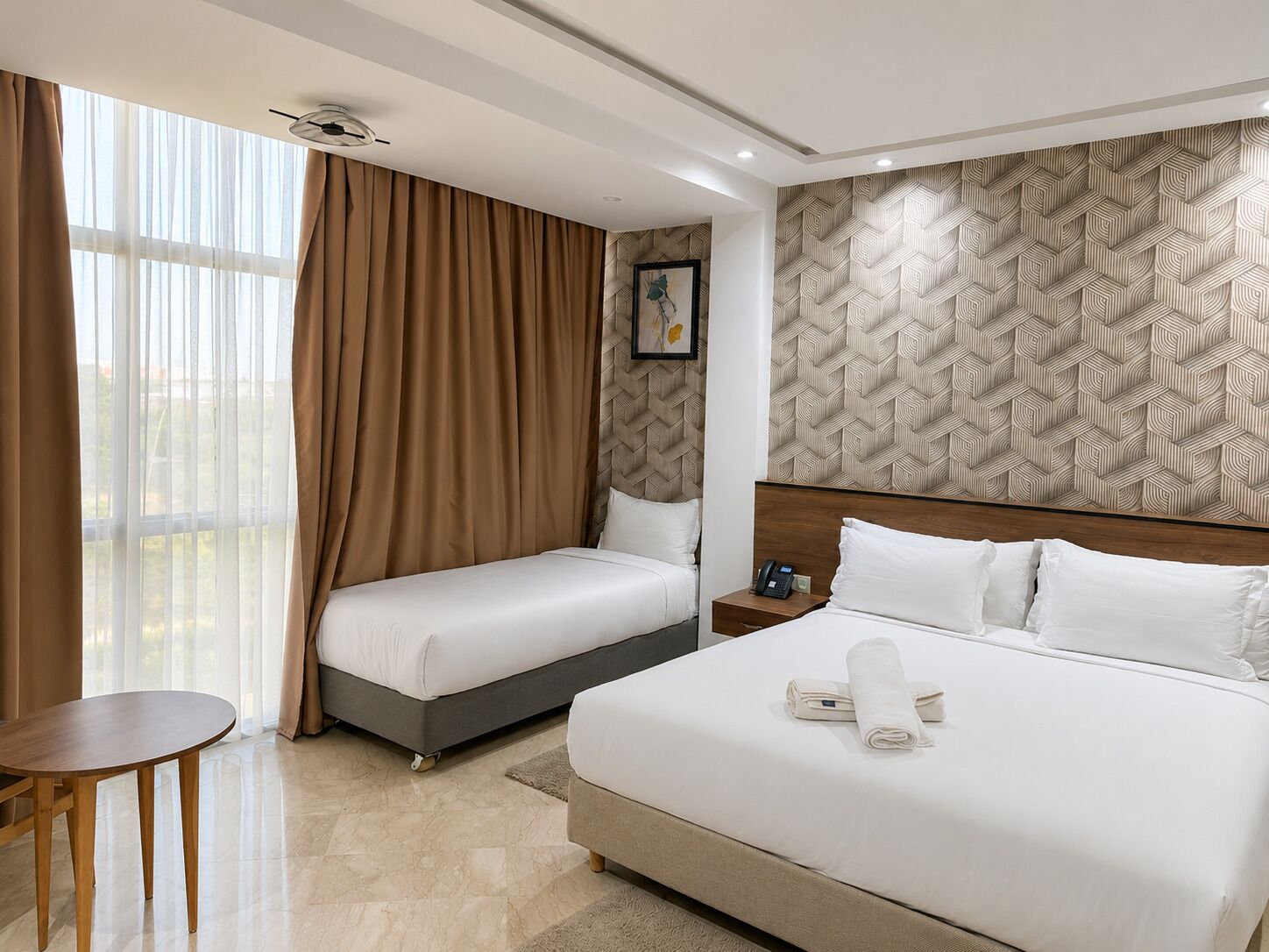 A hotel room with a large bed, a smaller bed, a desk, and a window with curtains.