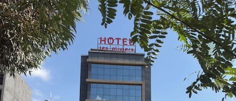Un moderno edificio de hotel con un letrero claro que dice 'HOTEL Les Olivier' y una entrada visible.
