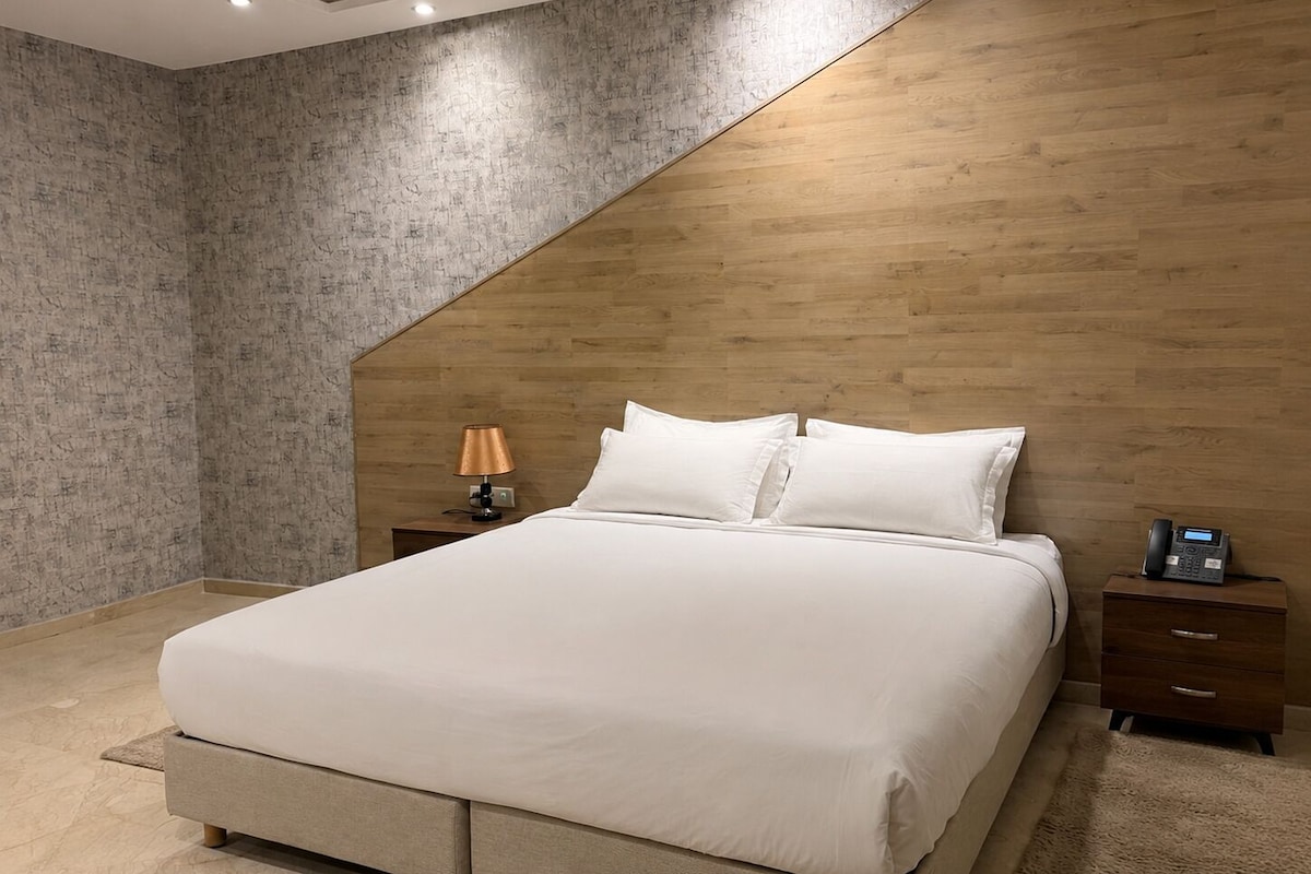 A modern bedroom with a bed, a nightstand, a lamp, and a telephone.