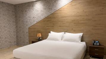 A modern bedroom with a bed, a nightstand, a lamp, and a telephone.
