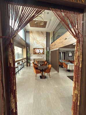 A modern dining area with a marble floor, wooden furniture, and a view of the adjacent room.