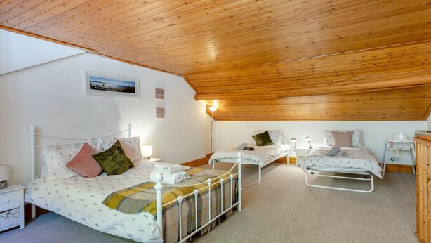 A bedroom with two beds, a wooden ceiling, and a small desk with a chair. - 3 Bed in Brixham (oc-c42670) (Brixham)