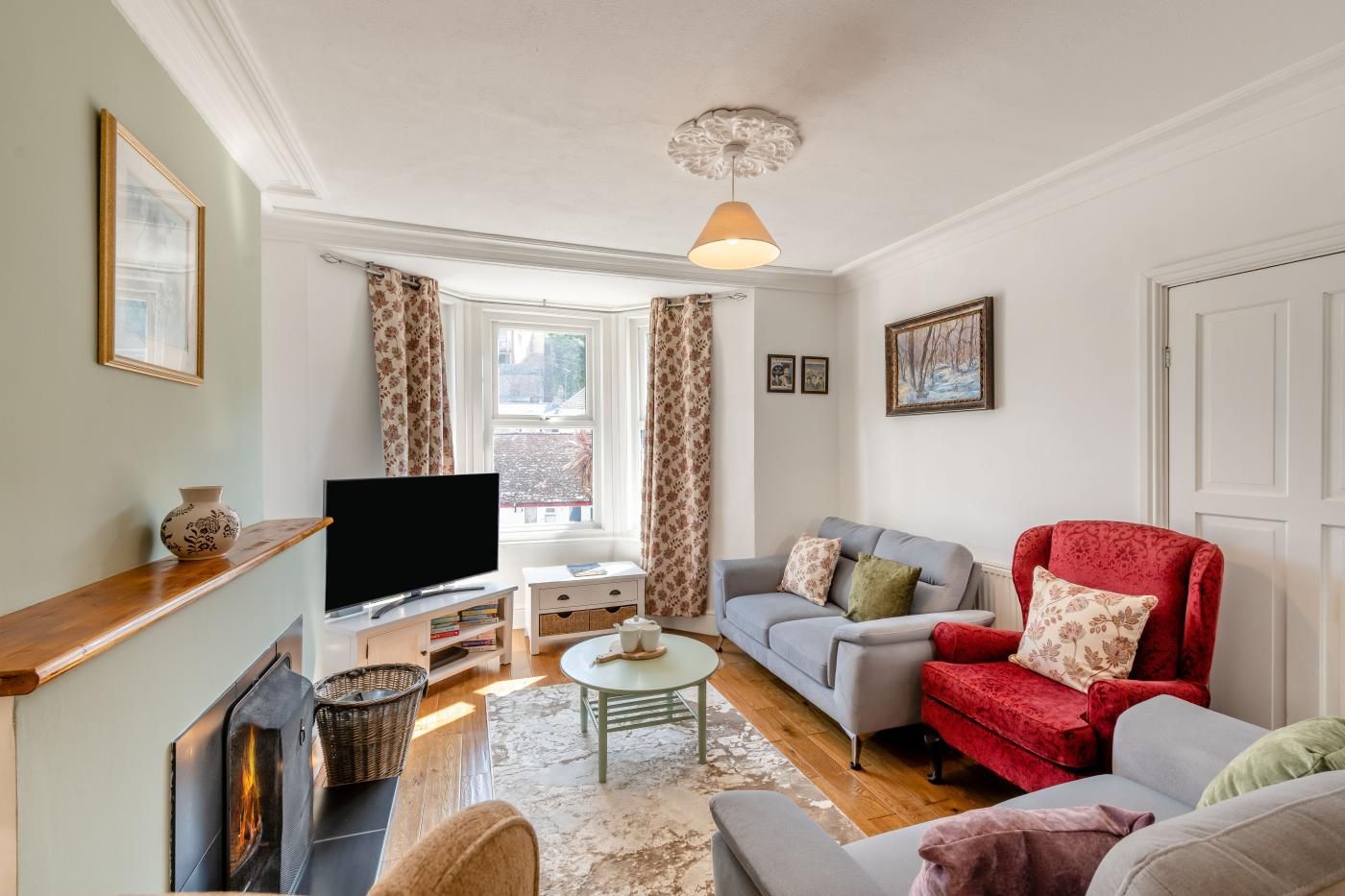 A living room with a television, sofa, armchair, and a fireplace.