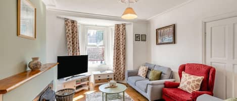 A living room with a television, sofa, armchair, and a fireplace.