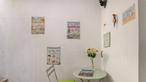 A room with a small table, a chair, and three posters on the wall. - 3 Bed in Brixham (oc-c42670) (Brixham)