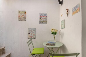 Um quarto com uma pequena mesa, uma cadeira e três quadros na parede.