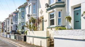 A row of terraced houses with bay windows, a white wall with a stone base, and a metal gate. - 3 Bed in Brixham (oc-c42670) (Brixham)