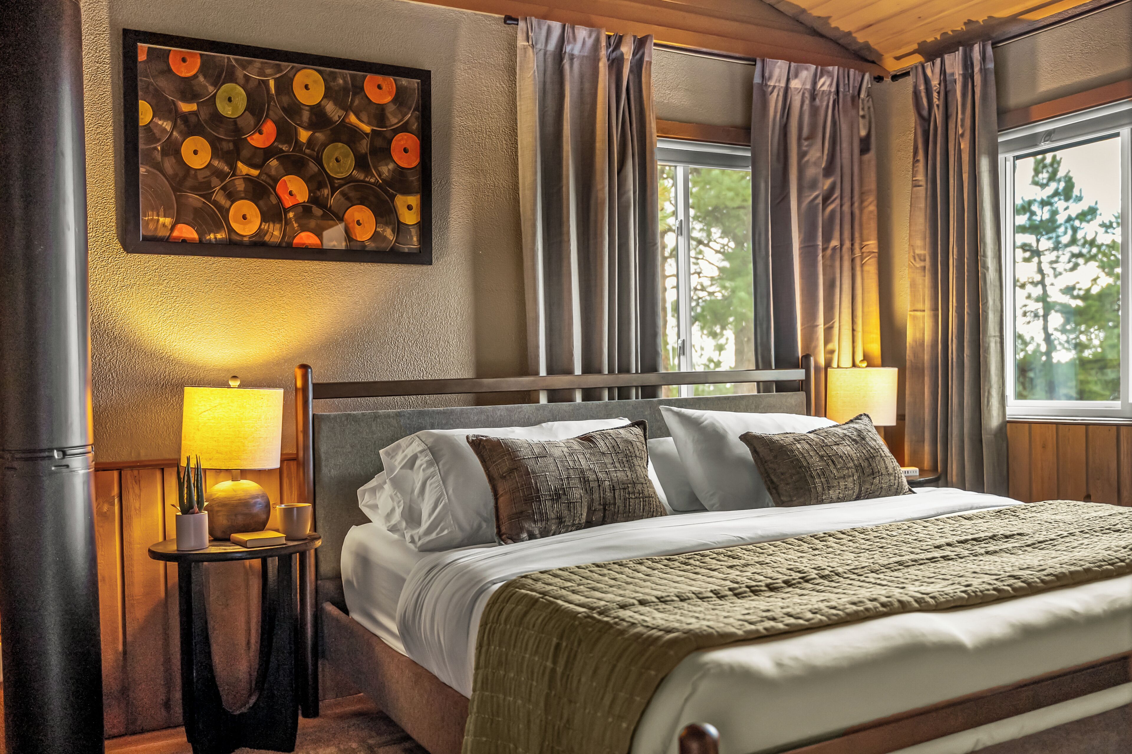 A hotel room with a bed, bedside lamps, a wall-mounted artwork, and a window with curtains.