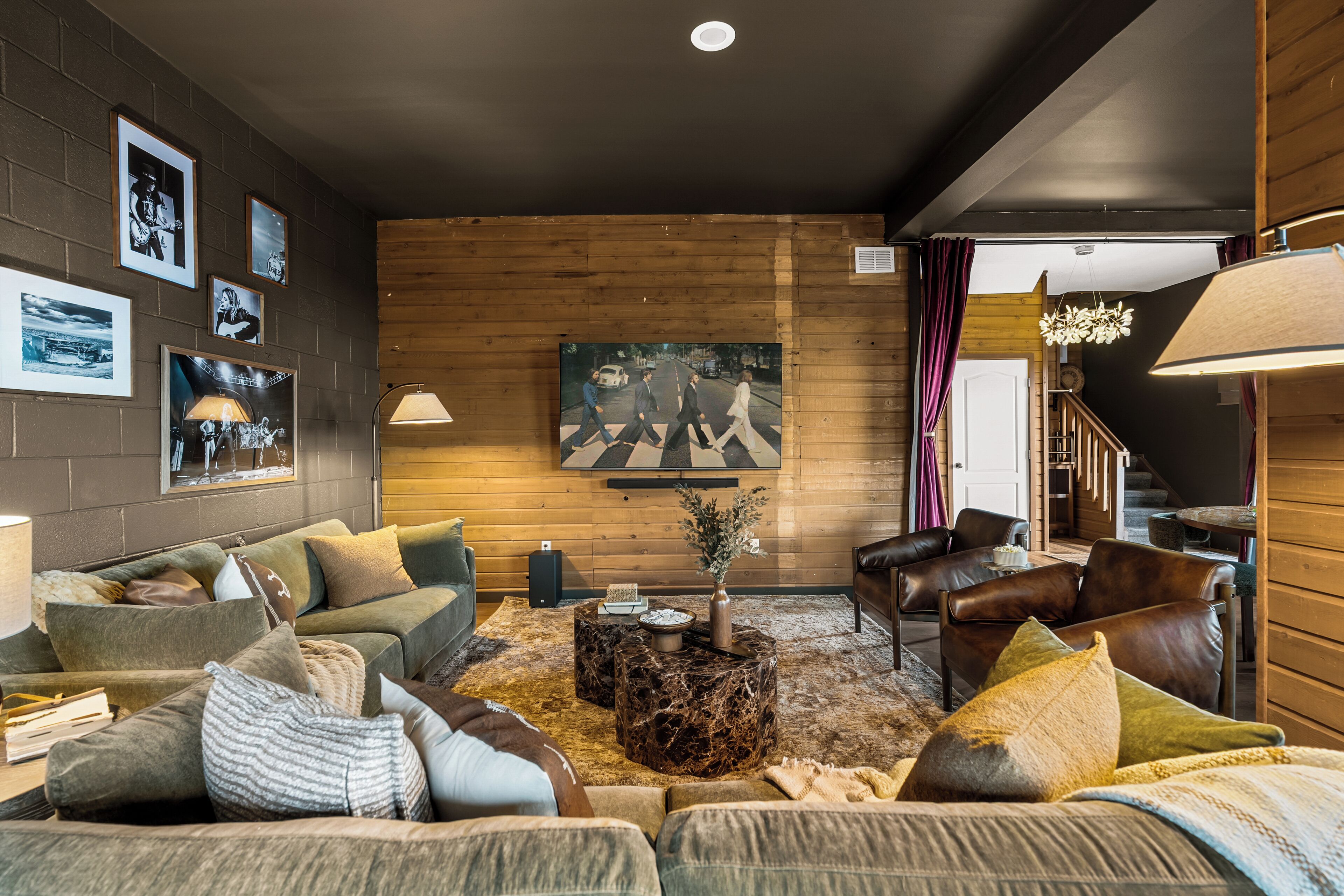 A cozy living room with a green sofa, a coffee table, and a painting of The Beatles on the wall.