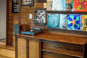 Een houten toonbank met een draaitafel, omringd door lijstwerken met albumhoezen.