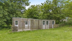 A wooden mobile home with a fenced yard, multiple doors, and a small porch. - 1 Bed in St. Florence (oc-d33551) (Saint Florence)