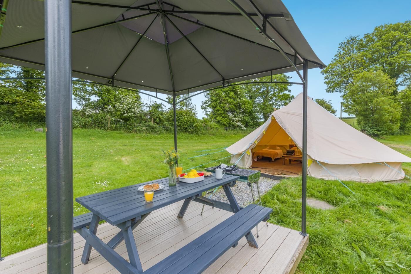 Eine Zelteinrichtung mit Picknicktisch und überdachter Sitzgelegenheit.