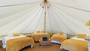 A tent with three beds, each with a yellow blanket and pillows, and a central table with a plant and a box of items. - 1 Bed in St. Florence (oc-d33551) (Saint Florence)