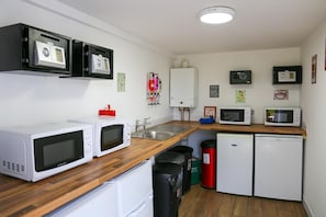 Eine kleine Küche mit weißen Geräten, einer Holz Arbeitsplatte und einem kleinen Kühlschrank.