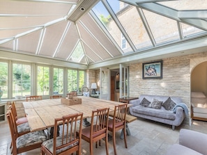 A spacious room with a large wooden dining table surrounded by chairs, a stone wall, and a glass ceiling. - 5 Bed in Burton Pedwardine (oc-g42735) (Burton Pedwardine)