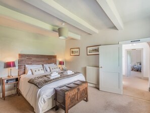A bedroom with a bed, bedside tables, a bench, a radiator, and a door leading to another room. - 5 Bed in Burton Pedwardine (oc-g42735) (Burton Pedwardine)