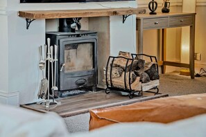 Ein Zimmer mit Kaminofen, Kaminvorsatz und Holzstapel.