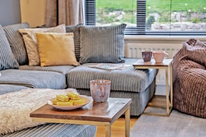 A cozy living room with a sofa, a coffee table with pastries, and a mug. - 6 Bed in Oakhill (oc-l33610) (Oakhill)