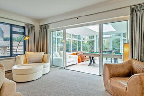 A modern living room with a pool table, a sofa, and a large sliding glass door leading to an outdoor area. - 6 Bed in Oakhill (oc-l33610) (Oakhill)