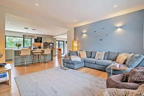 A modern living room with a sectional sofa, a dining area with bar stools, and a kitchen with a large island. - 6 Bed in Oakhill (oc-l33610) (Oakhill)