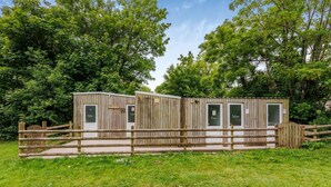 En træhytte med hegnede indgange, en lille veranda og en dør med teksten 'Bathroom'.