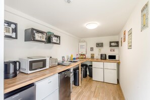 A compact kitchen with a microwave, toaster, and sink. There are black trash bins and a white refrigerator. - 1 Bed in St. Florence (oc-s33553) (Saint Florence)
