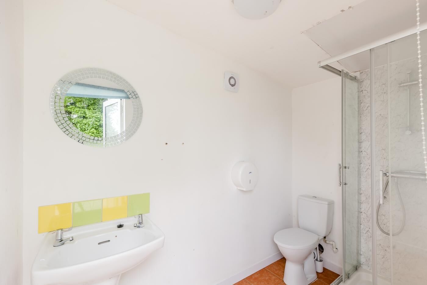 Et badeværelse med vask, toilet og brusekabine i glas.