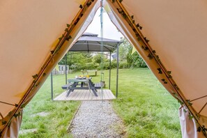 Ein Zelt mit Picknicktisch und überdachter Sitzgelegenheit in einer grünen Wiese.