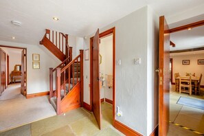Ein mehrgeschossiges Haus mit einer Holztreppe, einem Essbereich und einem Badezimmer.