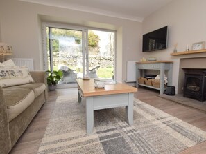 Ein Wohnzimmer mit Sofa, Couchtisch, Kamin und Fernseher.