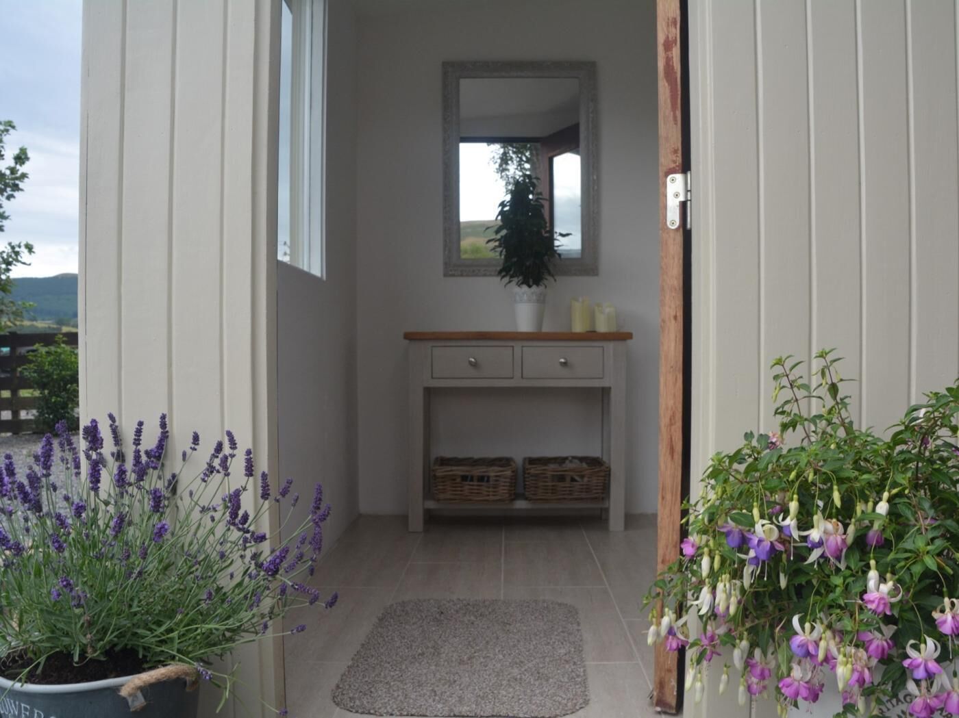 Un couloir avec un banc en bois, un miroir et une plante en pot.